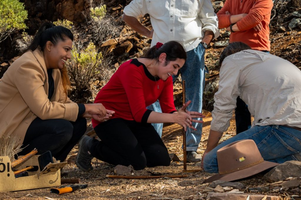 Zoha (middle) trying her own hand at traditional fire-making with Adnyamathanha guide Izzy (right) during the study tour to the Ikara-Flinders Ranges National Park in South Australia.