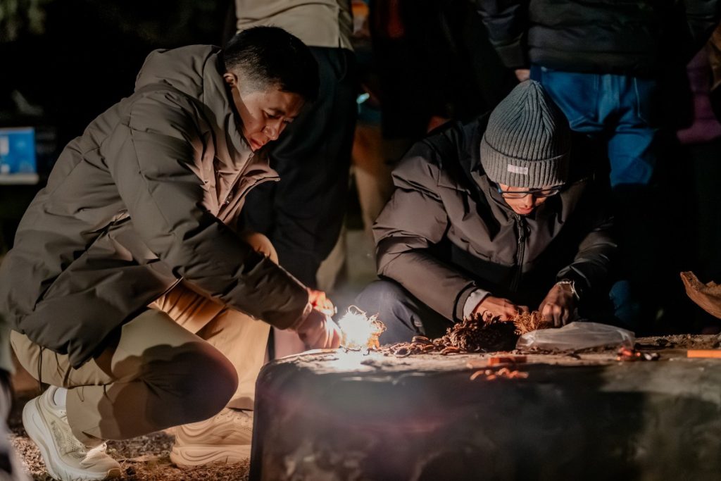 Dorji (left) engaged in a fire-making exercise under the guidance of John.